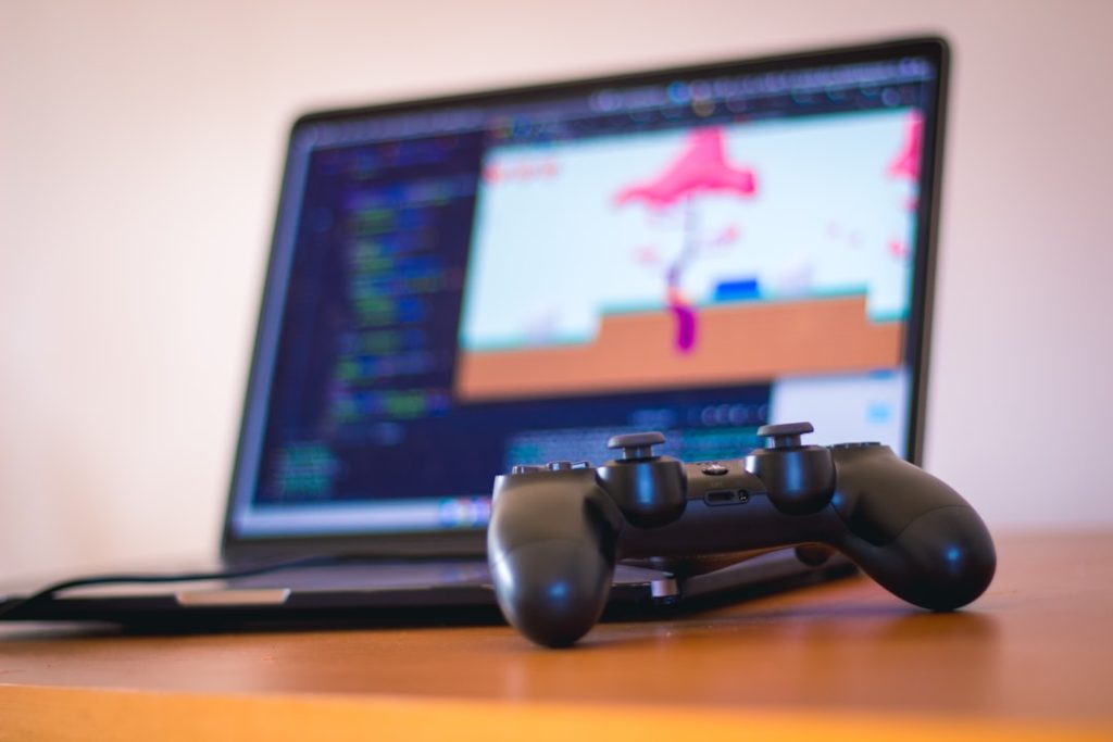 black-laptop-computer-beside-controller-on-brown-wooden-surface-xc3fq-ffxri